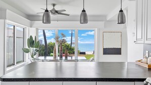 A kitchen with a large island, pendant lights, a ceiling fan, and a view of the ocean. - Oceanfront Villa With Privet Beach Access ! (Fort Lauderdale)