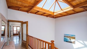 Ein geräumiger Innenraum mit einer Holztreppe, einem Oberlicht und einem Gemälde an der Wand.