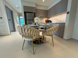 Une cuisine moderne avec un coin repas comprenant des chaises capitonnées aux pieds dorés.