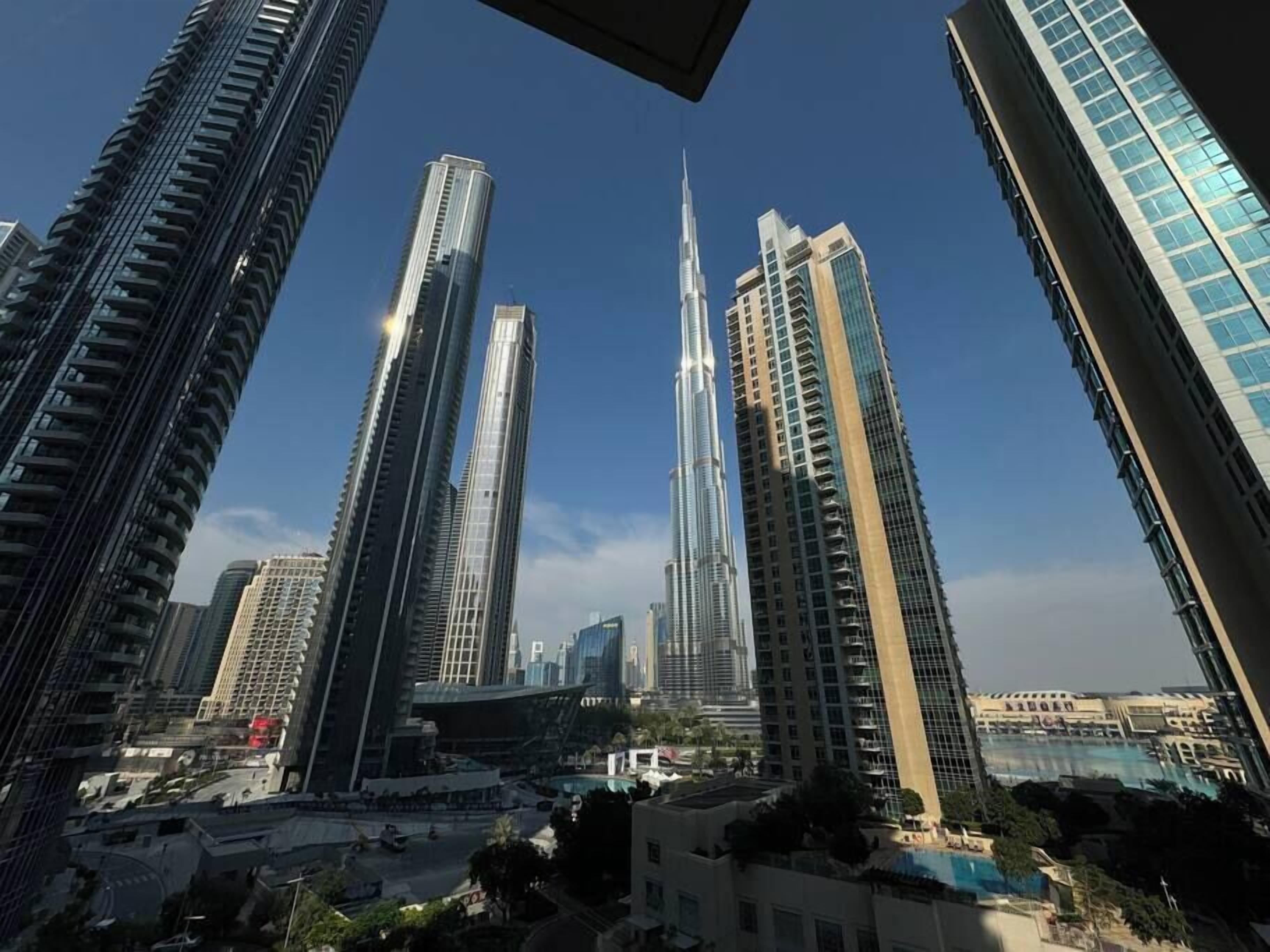Un quartier urbain dense, caractérisé par de nombreux immeubles de grande hauteur et des gratte-ciel modernes, dont une tour imposante surmontée d’une flèche.