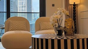 A modern living room with two white armchairs, a round black and white striped table, and a vase with white orchids.
