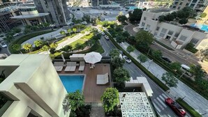 A high-rise building with a rooftop pool, lounge area, and a view of the surrounding urban landscape.