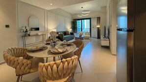 A modern kitchen with a dining area, featuring a round table with chairs, a refrigerator, and a large window providing natural light.