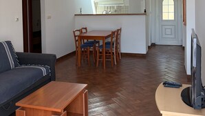 Una sala de estar con sofá, mesa de centro, televisor y un comedor con sillas y mesa.