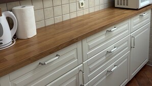 Cocina con encimera de madera, armarios blancos y microondas.