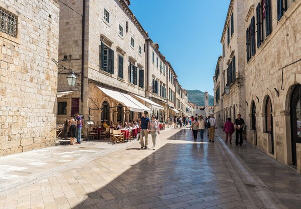 A historic street with stone buildings, outdoor seating, and a clear sky. - Apartment Lee Loo (Dubrovnik)