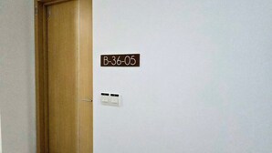 En hall med en dörr av trä och en skylt som sitter på väggen och som visar texten "B-36-05".