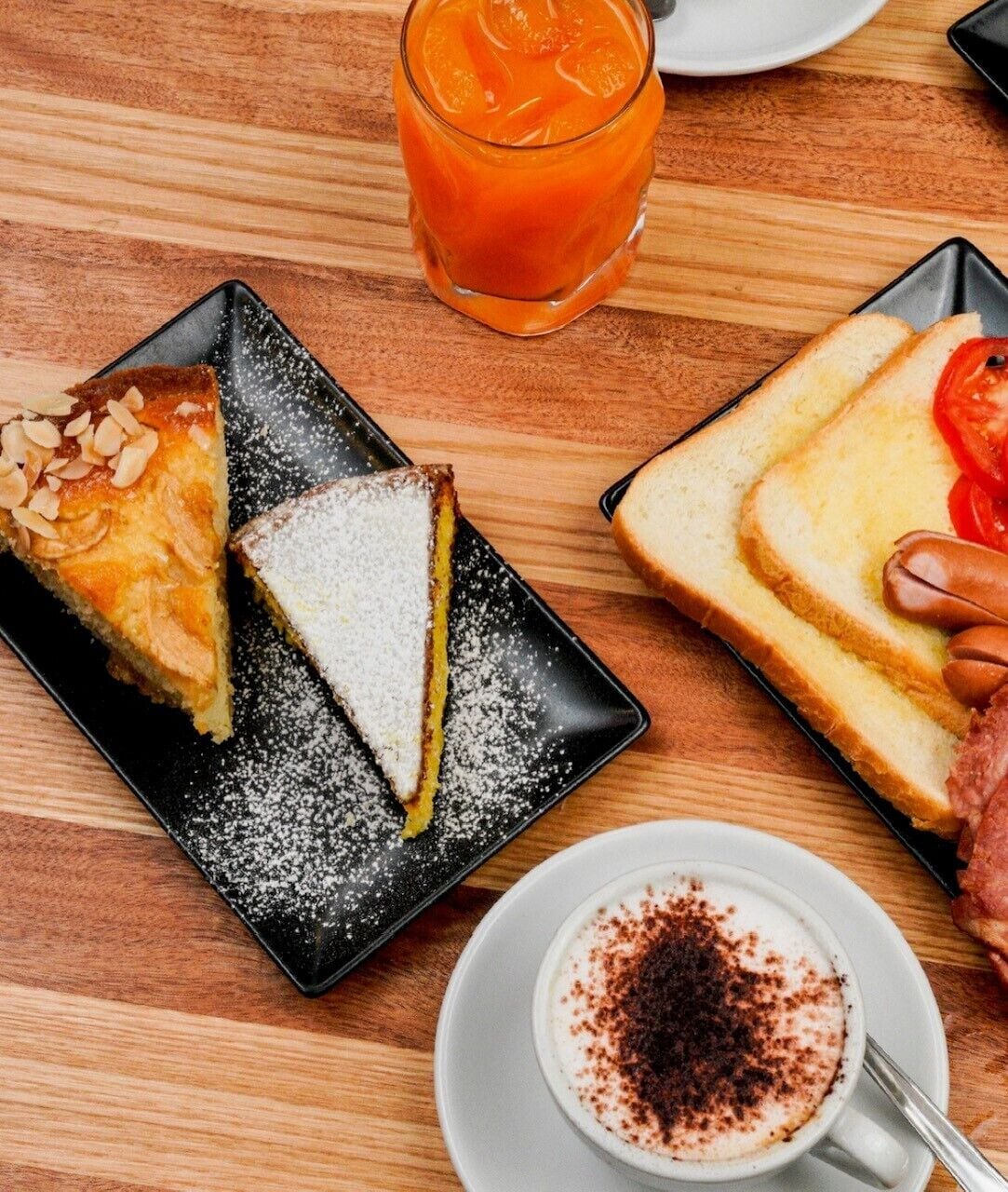 A table with a slice of pie, a sandwich, and a glass of juice.