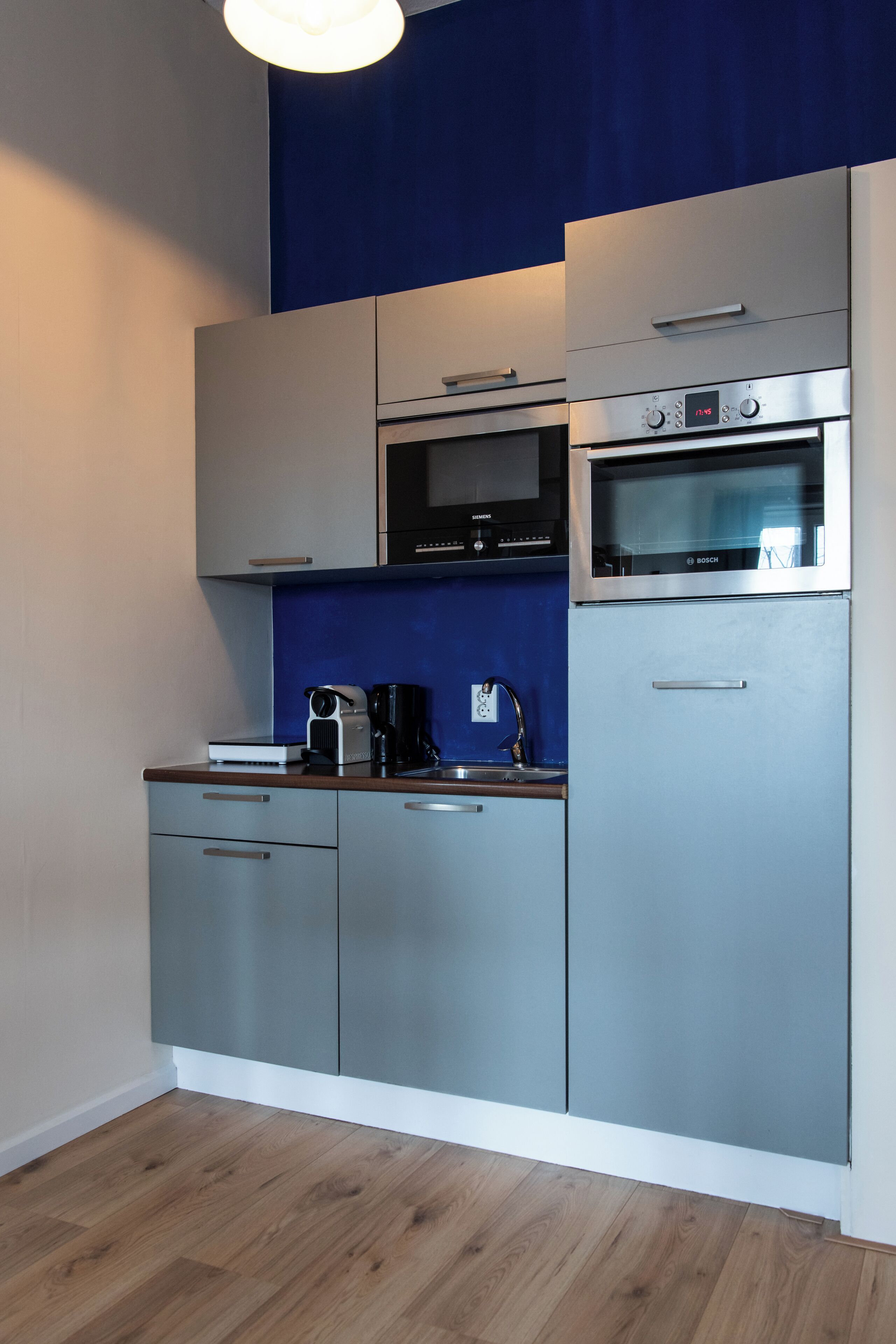 A modern kitchen with grey cabinets, a Bosch oven, and a coffee maker on the counter.