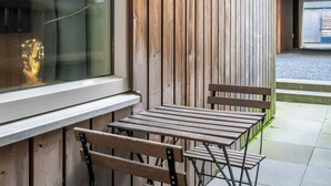 Un área de estar al aire libre con mesas y sillas de madera, un ventanal y una pared de madera.