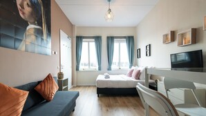 Un dormitorio moderno con cama, sofá, escritorio y televisor.