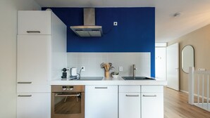 Cocina moderna con armarios blancos, horno empotrado, cafetera y una pared de acento azul.