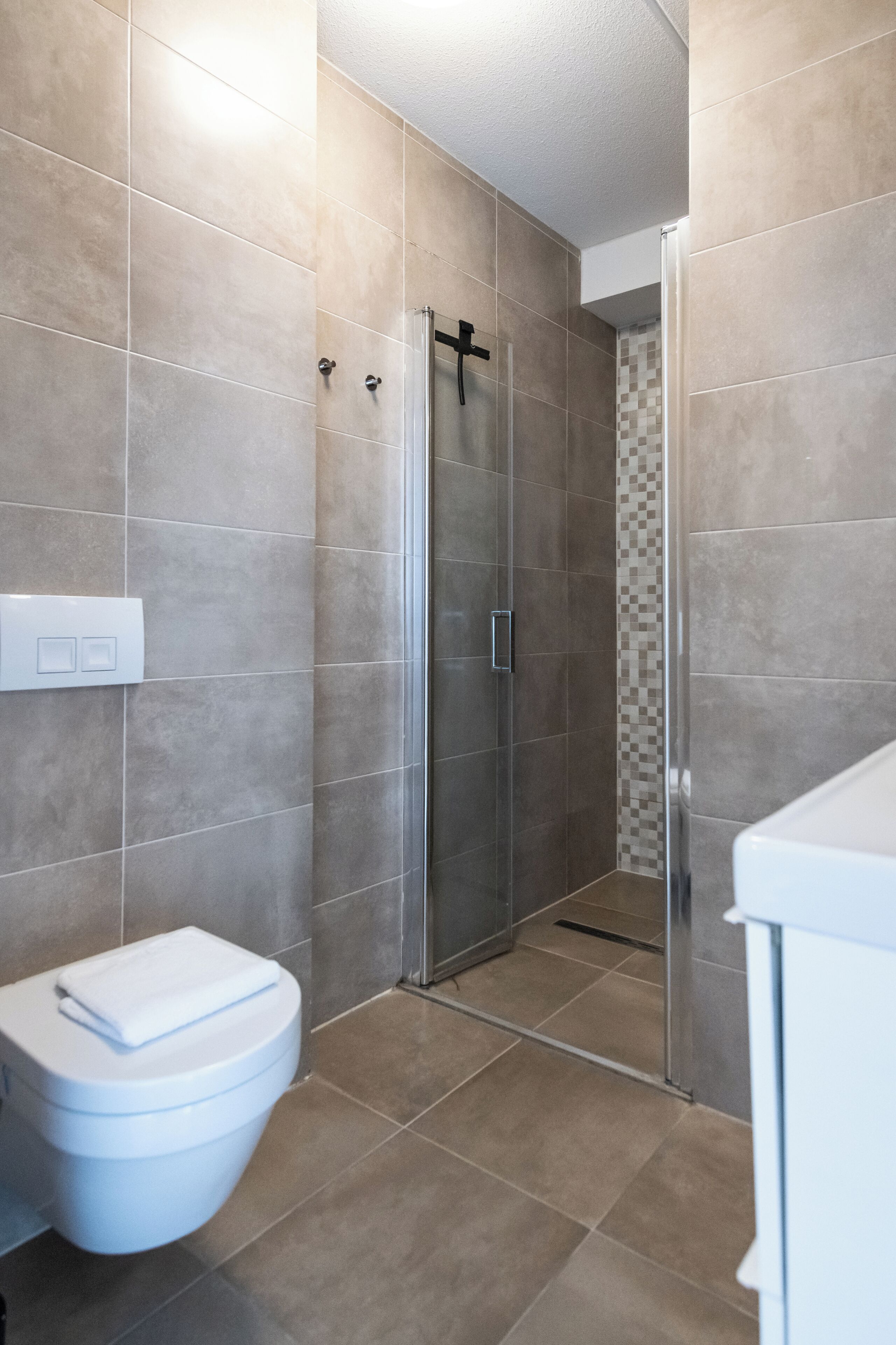 A bathroom with a toilet, shower, and tiled walls.