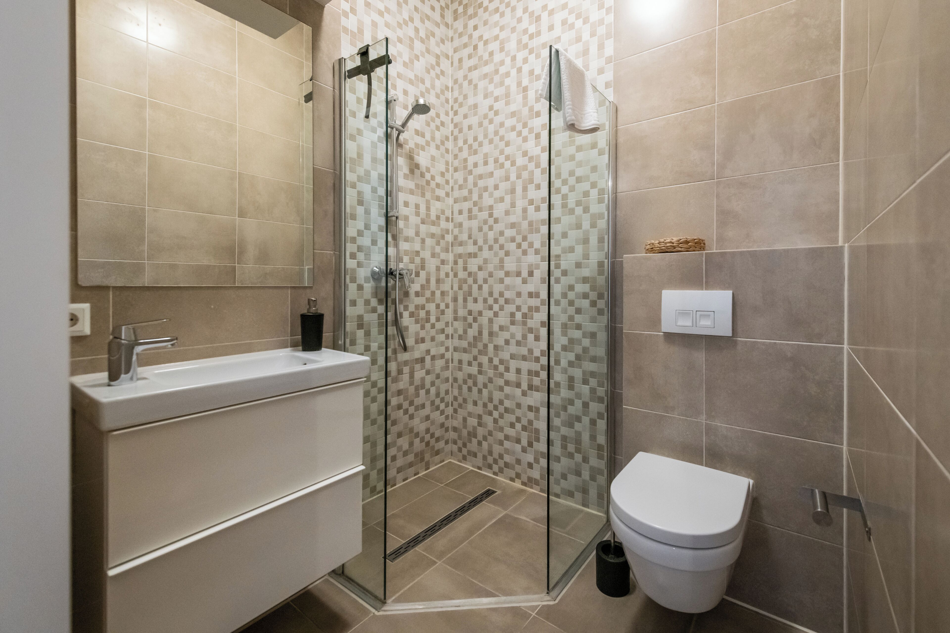 Ein modernes Badezimmer mit Duschkabine aus Glas, einem weißen Waschbecken und einer Toilette.