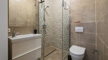 Ein modernes Badezimmer mit Duschkabine aus Glas, einem weißen Waschbecken und einer Toilette.