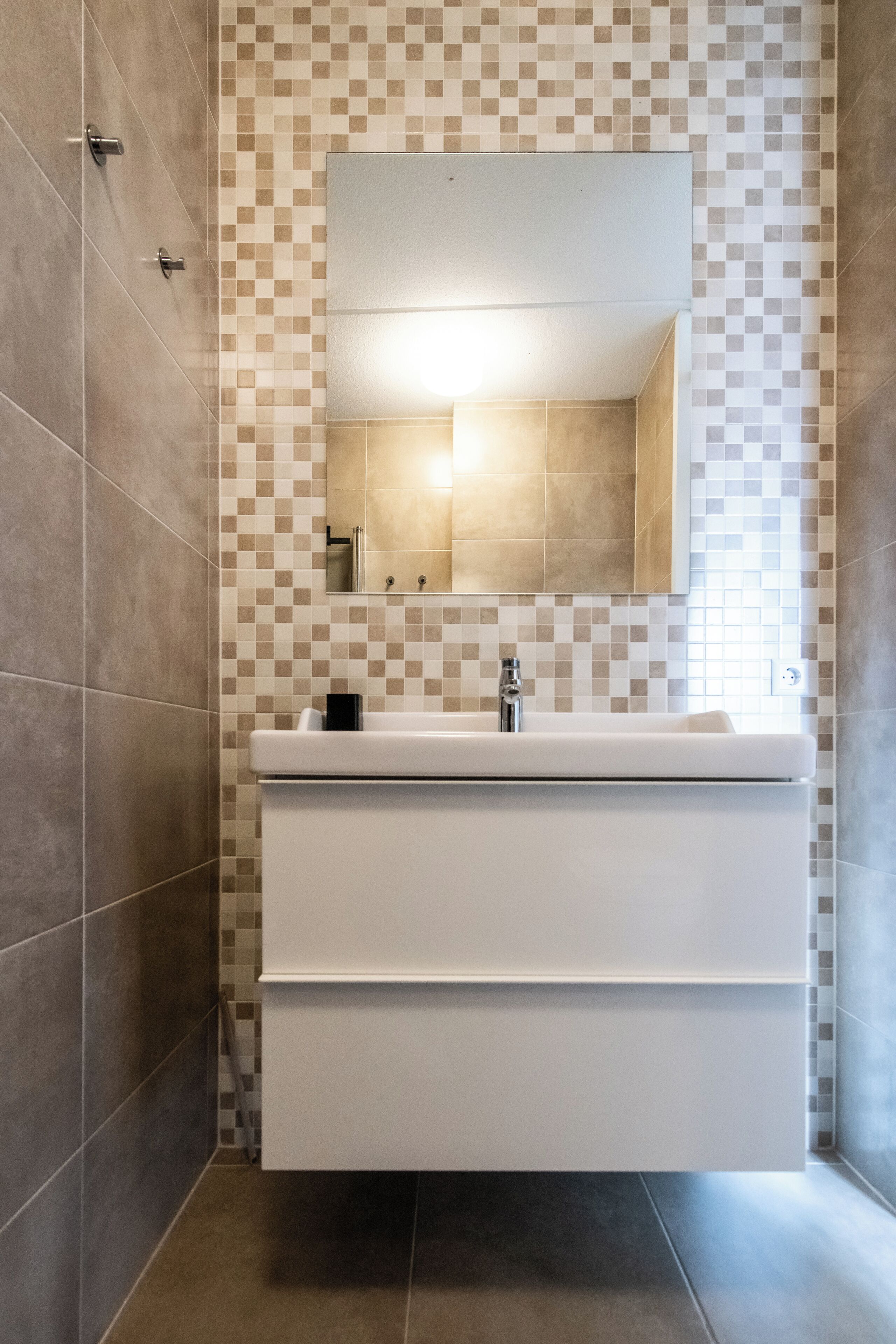 A bathroom with a tiled backsplash, a white sink, and a mirror.