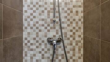 Een douche met een betegelde muur in ruitpatroon en een handdouche.