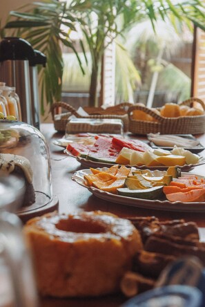 Un bufé de desayuno con diversas frutas, quesos y pasteles.