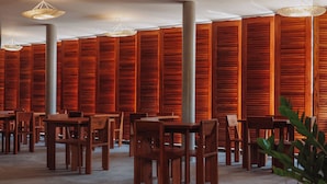 Een kamer met houten lambrisering, meerdere tafels en stoelen, en hangende吊灯.