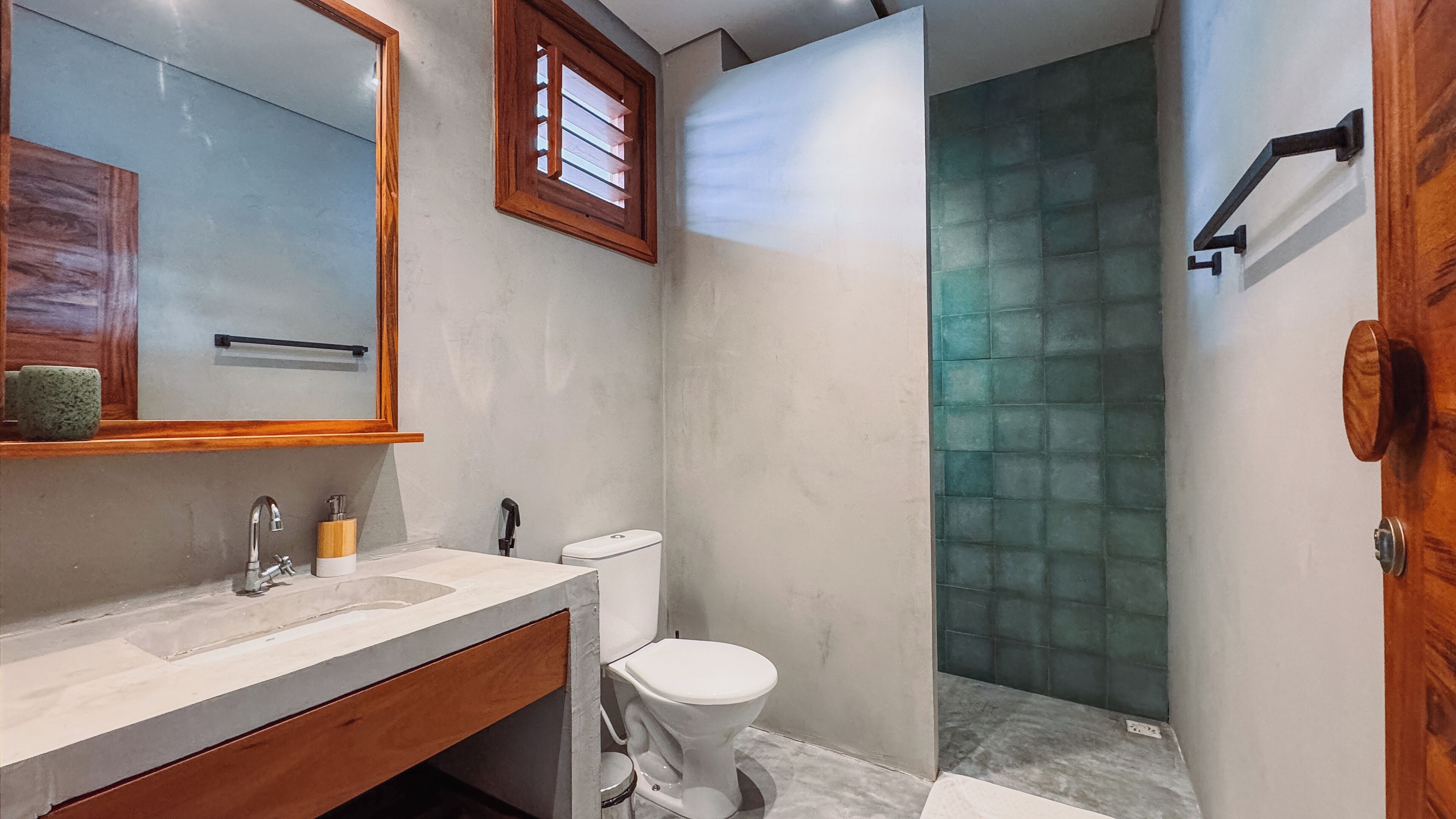 Une salle de bain avec un meuble-lavabo en bois, des toilettes blanches et une cabine de douche en verre.