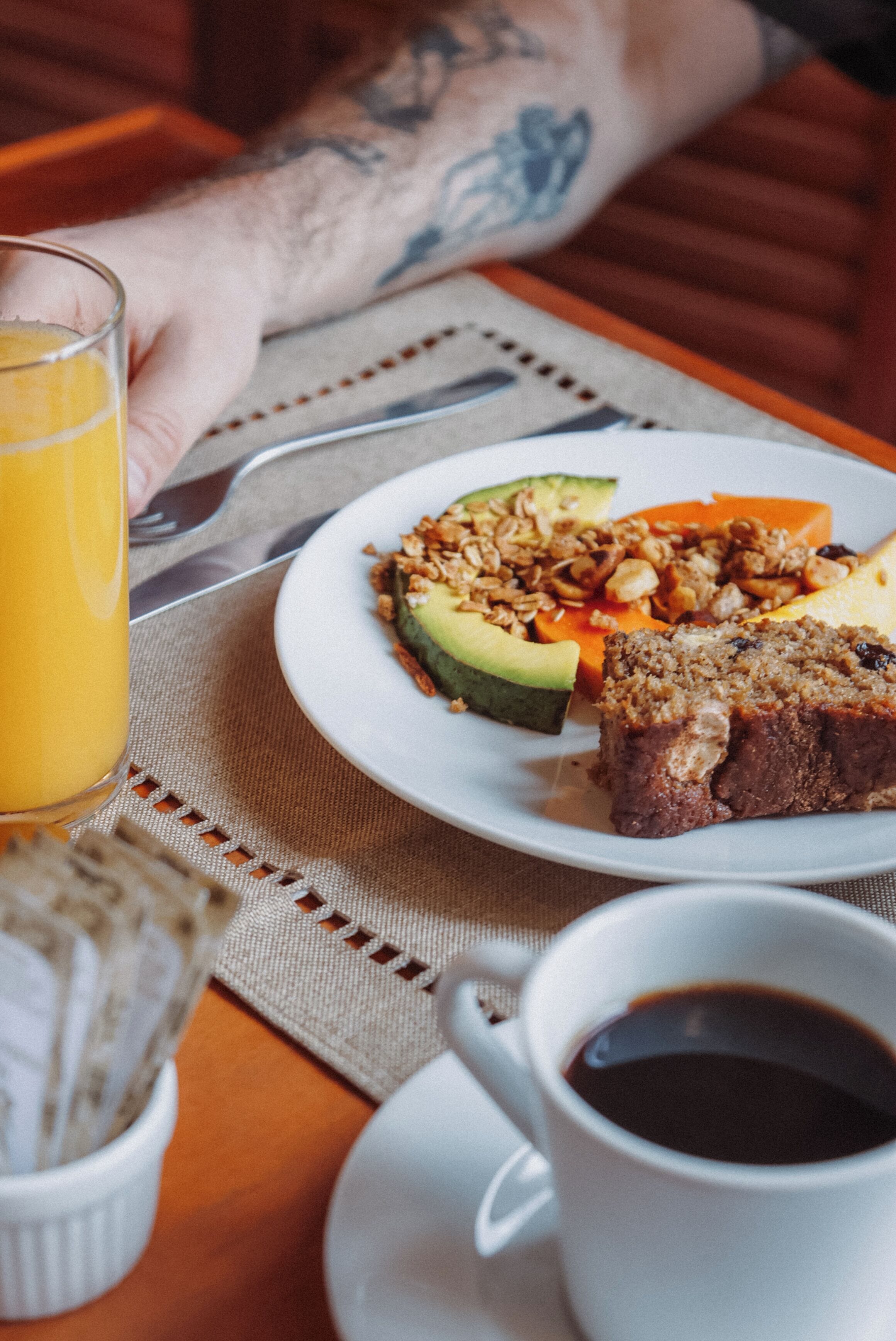 A breakfast setting with a plate of food, a glass of orange juice, and a cup of coffee on a table.