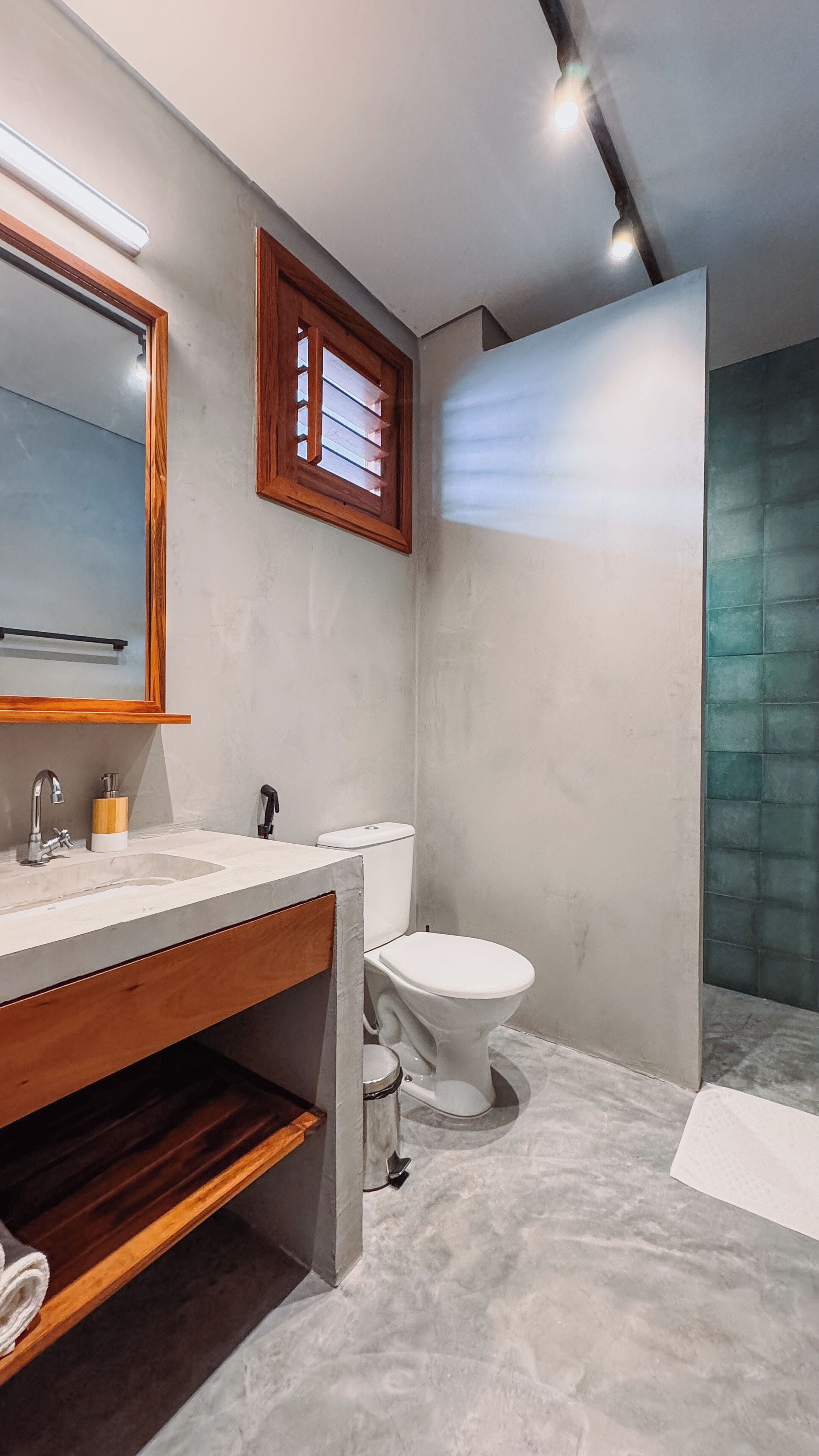 A modern bathroom with a wooden vanity, a large mirror, a toilet, and a shower area.