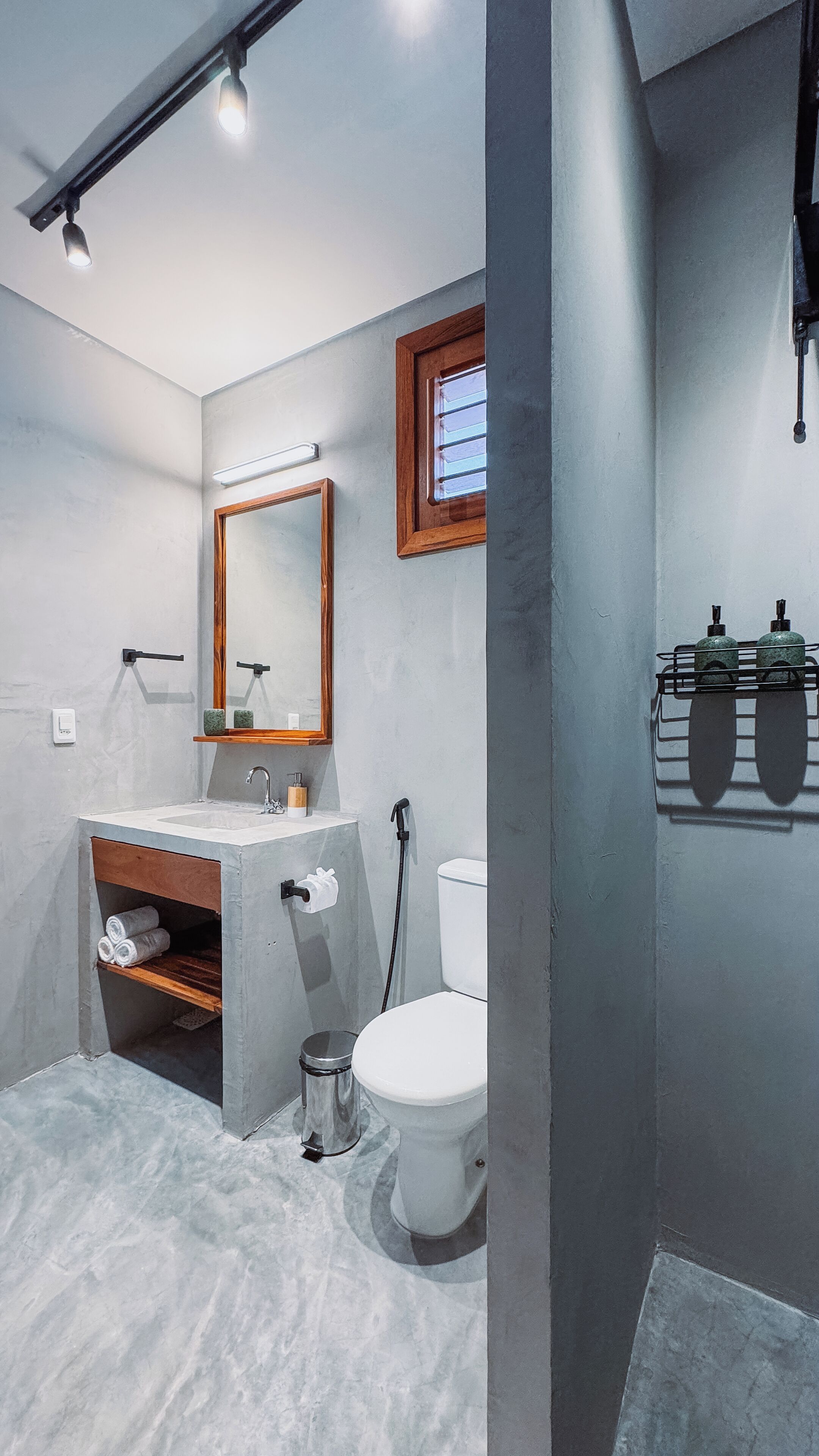 A modern bathroom with a large mirror, a toilet, a sink, and a shower.