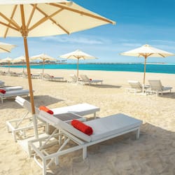 Praia particular, areia branca, espreguiçadeiras, guarda-sóis