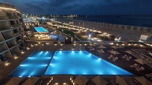 A resort with a large swimming pool, beachside lounge areas, and a view of the ocean.