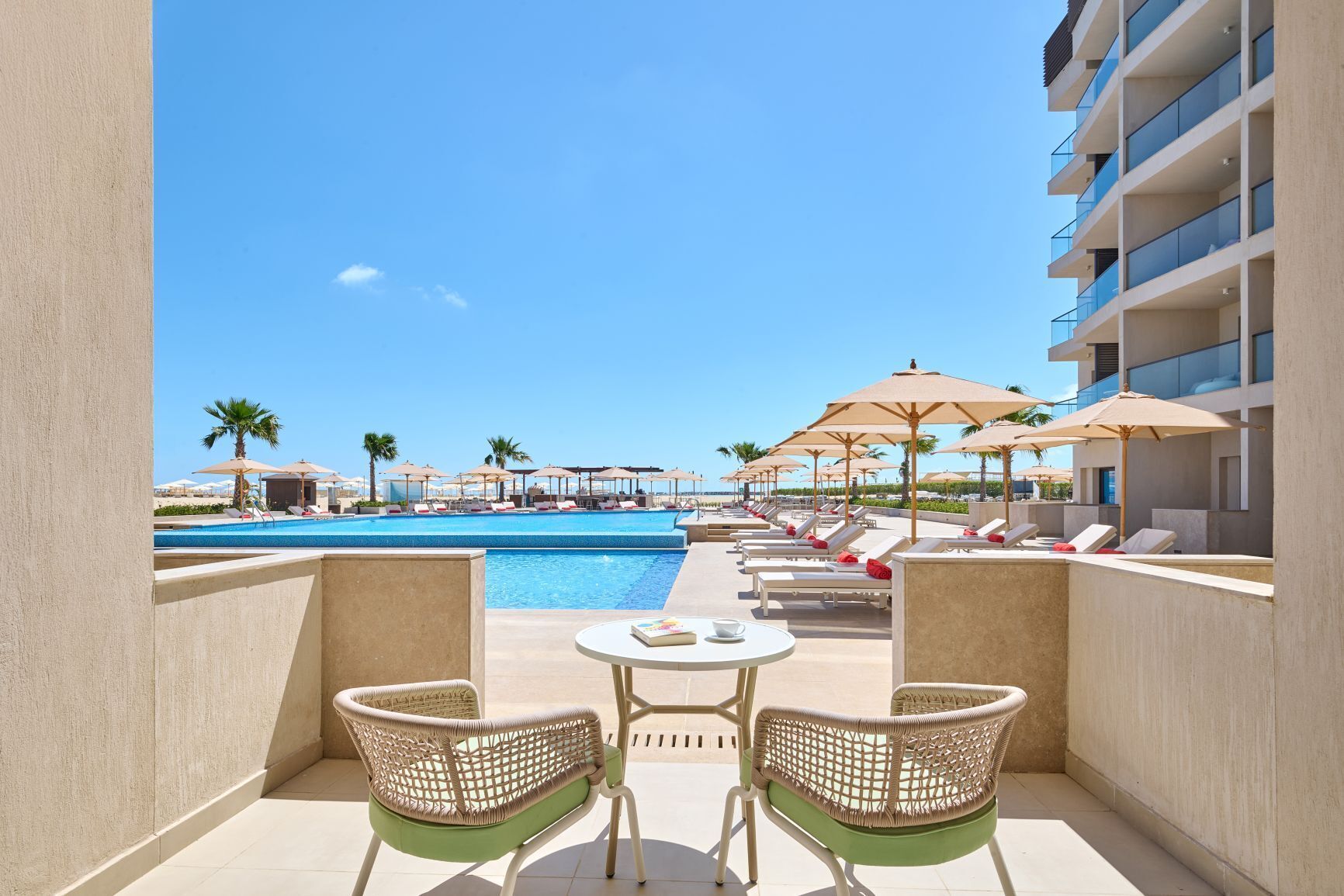 A poolside area with lounge chairs, umbrellas, and a view of a swimming pool.