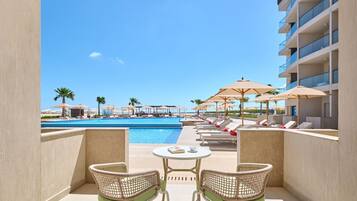 A poolside area with lounge chairs, umbrellas, and a view of a swimming pool.