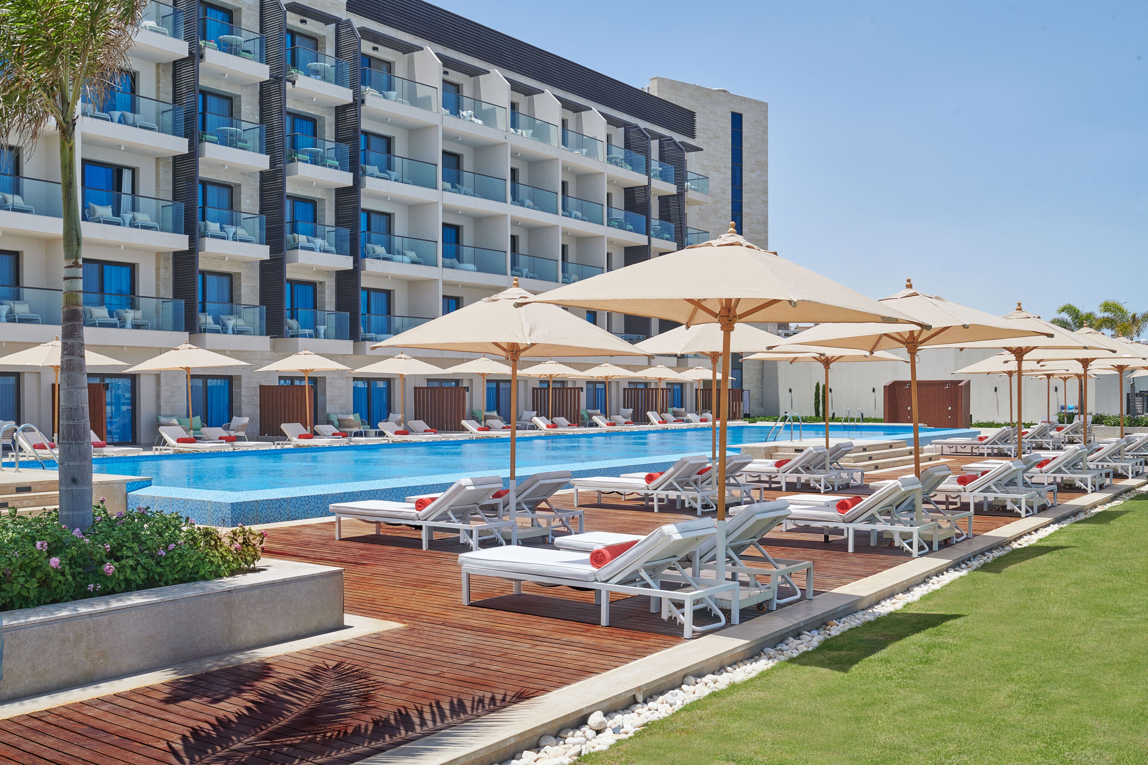 Un hôtel doté d’une piscine, de chaises longues et de parasols.