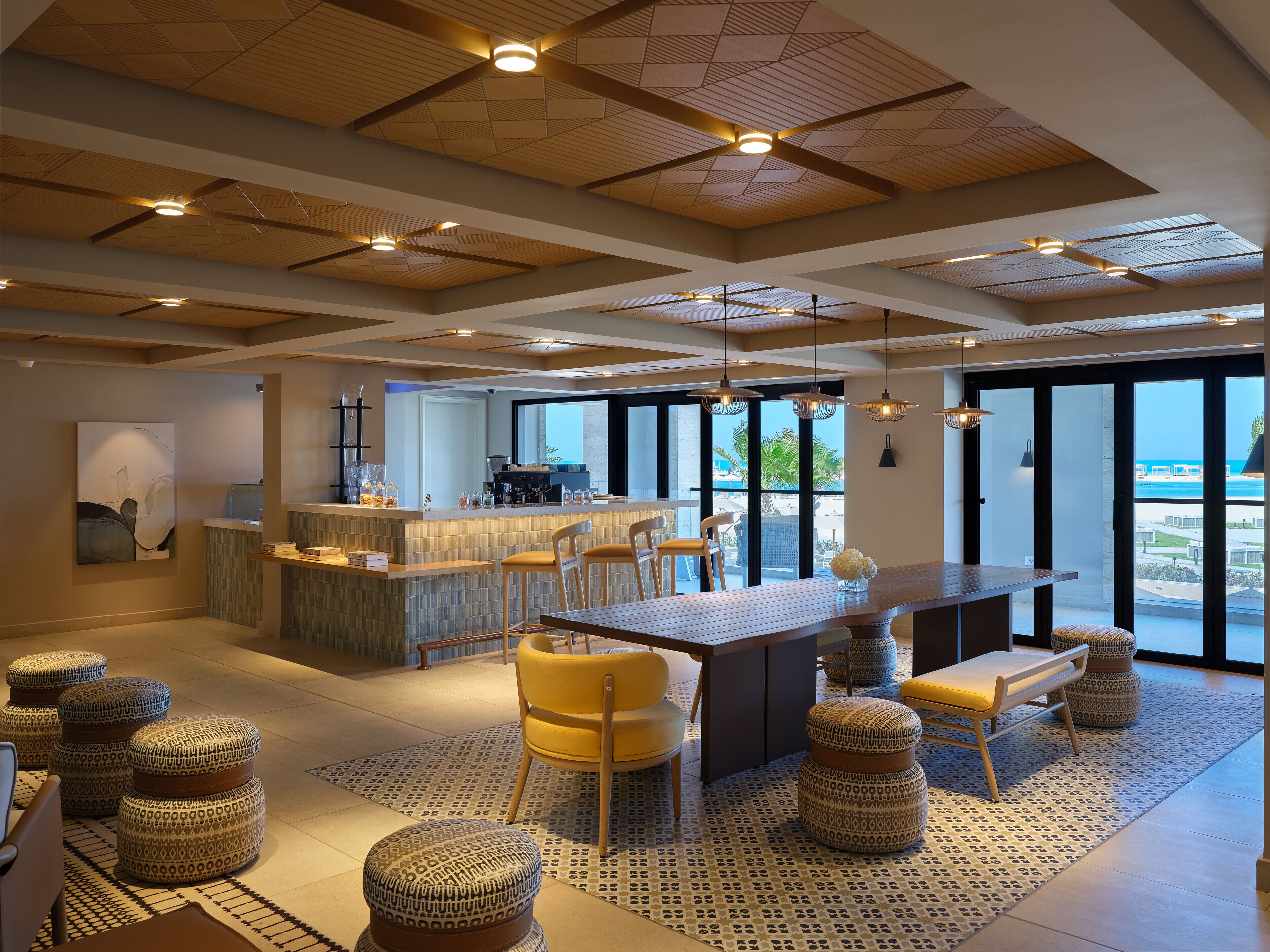 A modern interior with a bar area, seating, and large windows offering a view.