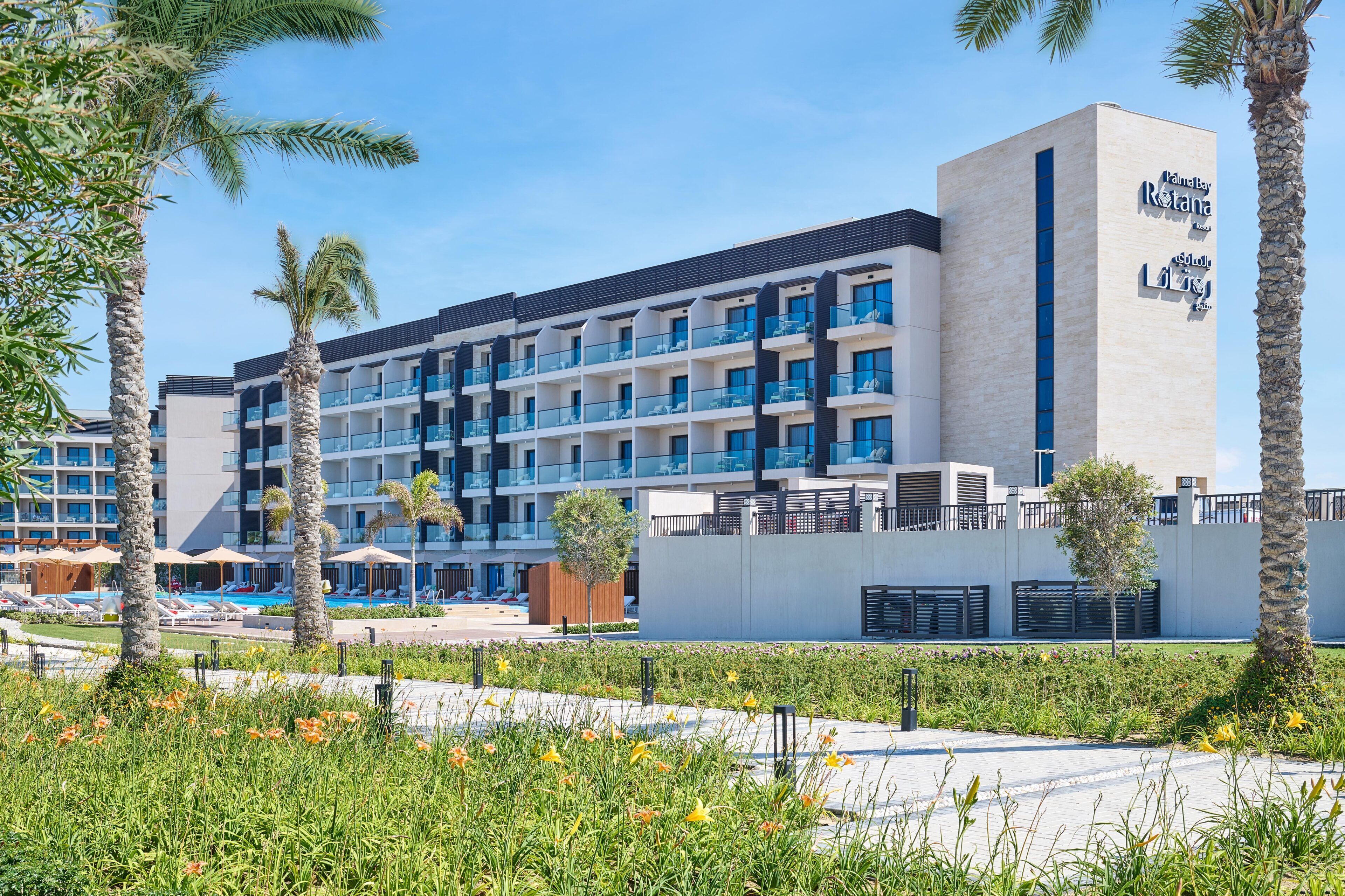 Un hotel moderno con varios pisos, balcones y una zona de piscina.