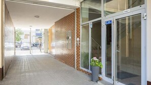 A corridor with a tiled floor leading to a glass door entrance. - Stylish Apartment in the Center | Balcony | View of the Palace of Culture and Science (Warszawa)