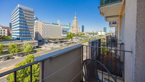 A balcony with a view of a cityscape, including a prominent building with a spire. - Stylish Apartment in the Center | Balcony | View of the Palace of Culture and Science (Warszawa)