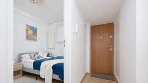 A modern bedroom with a bed, bedside table, and a door leading to another room. - Stylish Apartment in the Center | Balcony | View of the Palace of Culture and Science (Warszawa)