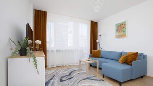 A modern living room with a blue sofa, a white coffee table, and a patterned rug. - Stylish Apartment in the Center | Balcony | View of the Palace of Culture and Science (Warszawa)