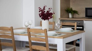 A dining table with four chairs, a vase with red flowers, and a television in the background. - Stylish Apartment in the Center | Balcony | View of the Palace of Culture and Science (Warszawa)