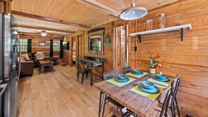 Un intérieur en bois comprenant une table à manger pour quatre personnes, un canapé et un coin cuisine.