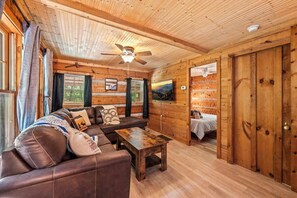 A wooden interior with a sofa, a table, and a bed.