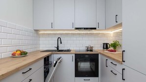 Una cucina moderna con mobili bianchi, un forno nero e un piano di lavoro in legno.