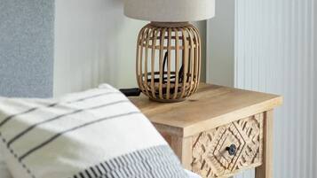 Ein Bett mit einem gestreiften Kopfkissen, ein Nachttisch aus Holz mit einer Lampe und ein Heizkörper im Hintergrund.