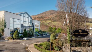 Un hotel moderno con fachada de vidrio, un letrero del Hotel Four Seasons y un bar restaurante Lough cercano.