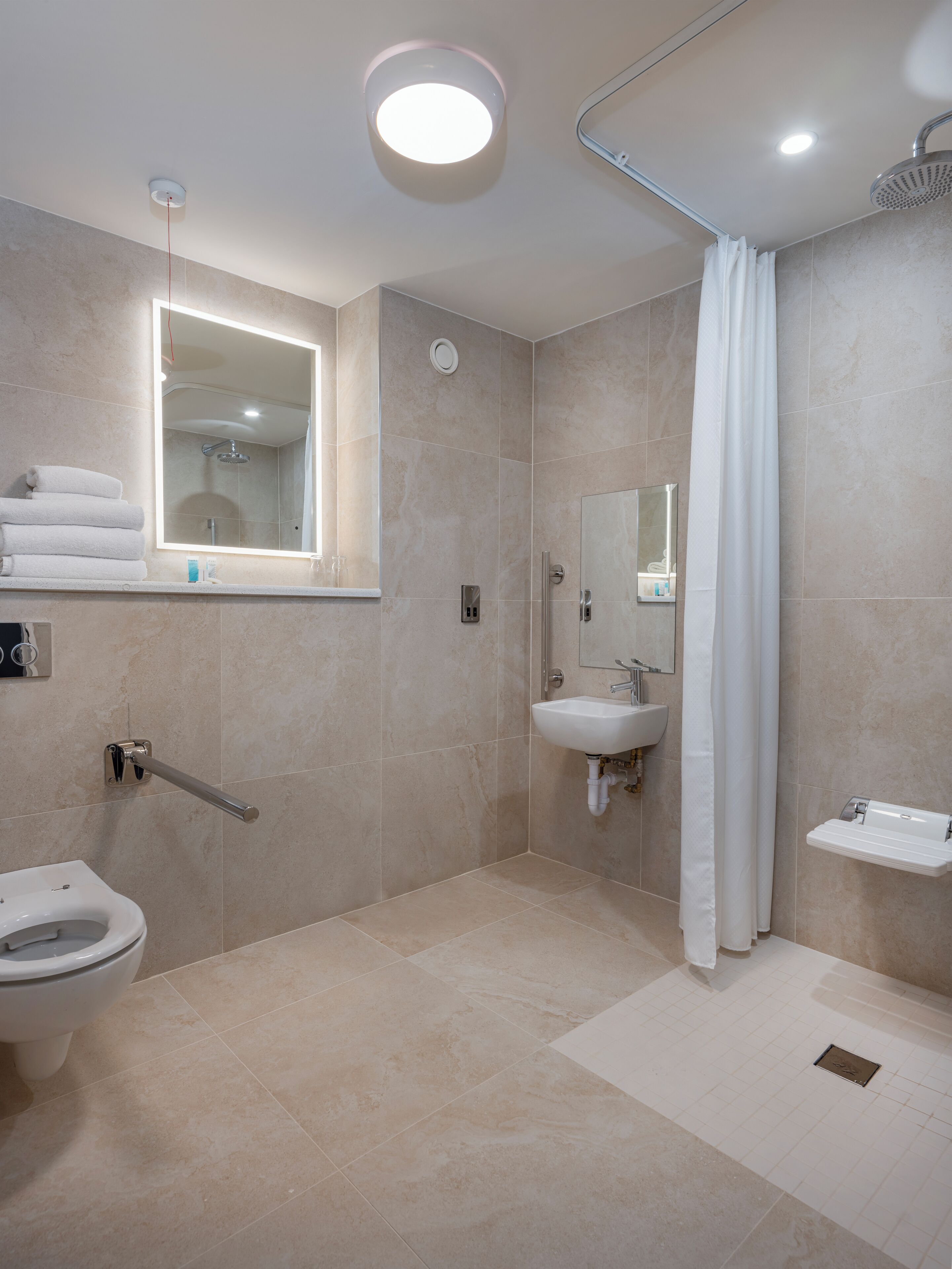 A modern bathroom with a toilet, sink, shower, and a mirror.