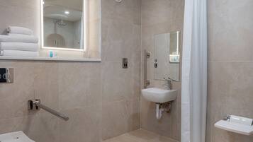 A modern bathroom with a toilet, sink, shower, and a mirror.