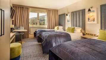 Habitación de hotel con dos camas, un escritorio, una silla y vistas al exterior.