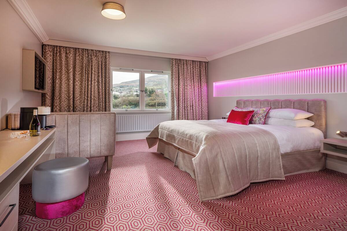 Habitación de hotel con cama, escritorio y ventana con cortinas.
