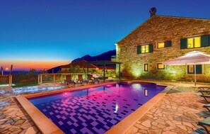 A stone building with a swimming pool, outdoor seating, and a mountain backdrop. - Villa Pave (Konavle)