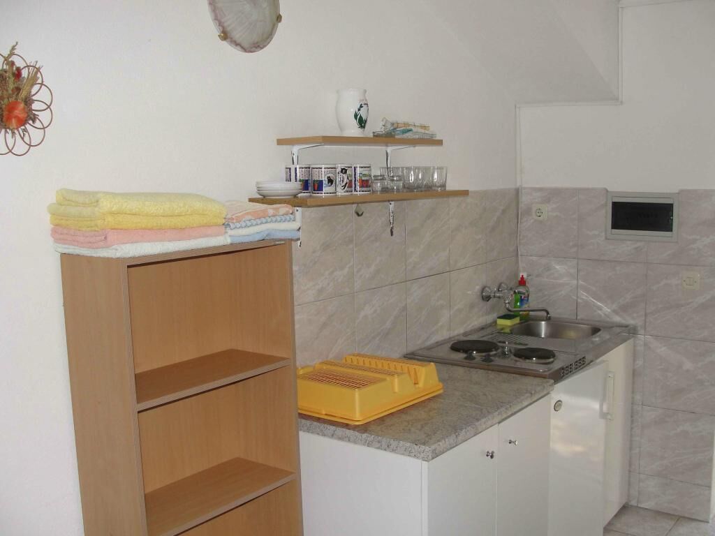 Una cucina compatta con lavandino, piano di lavoro e pensile in legno.